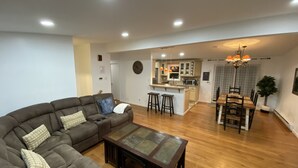 A modern living room with a sectional sofa, a glass-top coffee table, and a dining area with a wooden table and chairs. - Creek house with expansive mountain views (ashland)