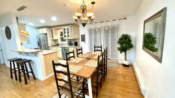 A modern kitchen with a central island, dining table with chairs, and a chandelier. - Creek house with expansive mountain views (ashland)