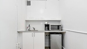 A compact kitchenette with a microwave, coffee maker, sink, and a small refrigerator. - Modern Beachfront Suite 309 (Ocean City)