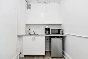 Une petite cuisine équipée d’un four à micro-ondes, d’une machine à café, d’un évier et d’un petit réfrigérateur.