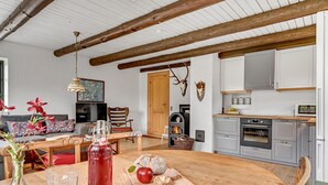 Een gezellige woonkamer met een open haard, een eettafel met brood en een appel, en een keuken met moderne apparatuur.