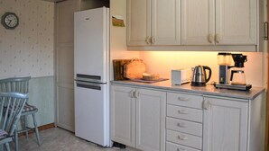 A kitchen with a white refrigerator, wooden cabinets, a clock, and a coffee maker. - Awesome apartment in Nybrostrand (Nybrostrand)