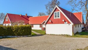 A two-story house with a red roof and white walls, a gravel driveway, and a well-maintained lawn. - Awesome apartment in Nybrostrand (Nybrostrand)