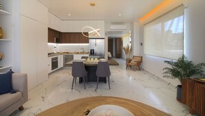A modern kitchen with white cabinets, a central island, and a dining area with a table and chairs. - Avida - Stunning Rooftop Pool and Jacuzzi (Puerto Vallarta)