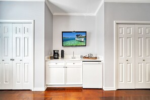 Ein Hotelzimmer mit einer Küchenzeile, einem Wand-Fernseher und Holzboden.