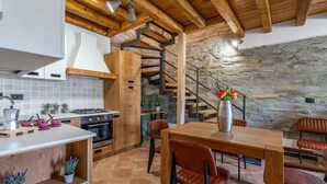 Eine rustikale Küche mit Holzbalken, einer Steinwand und einer Wendeltreppe.