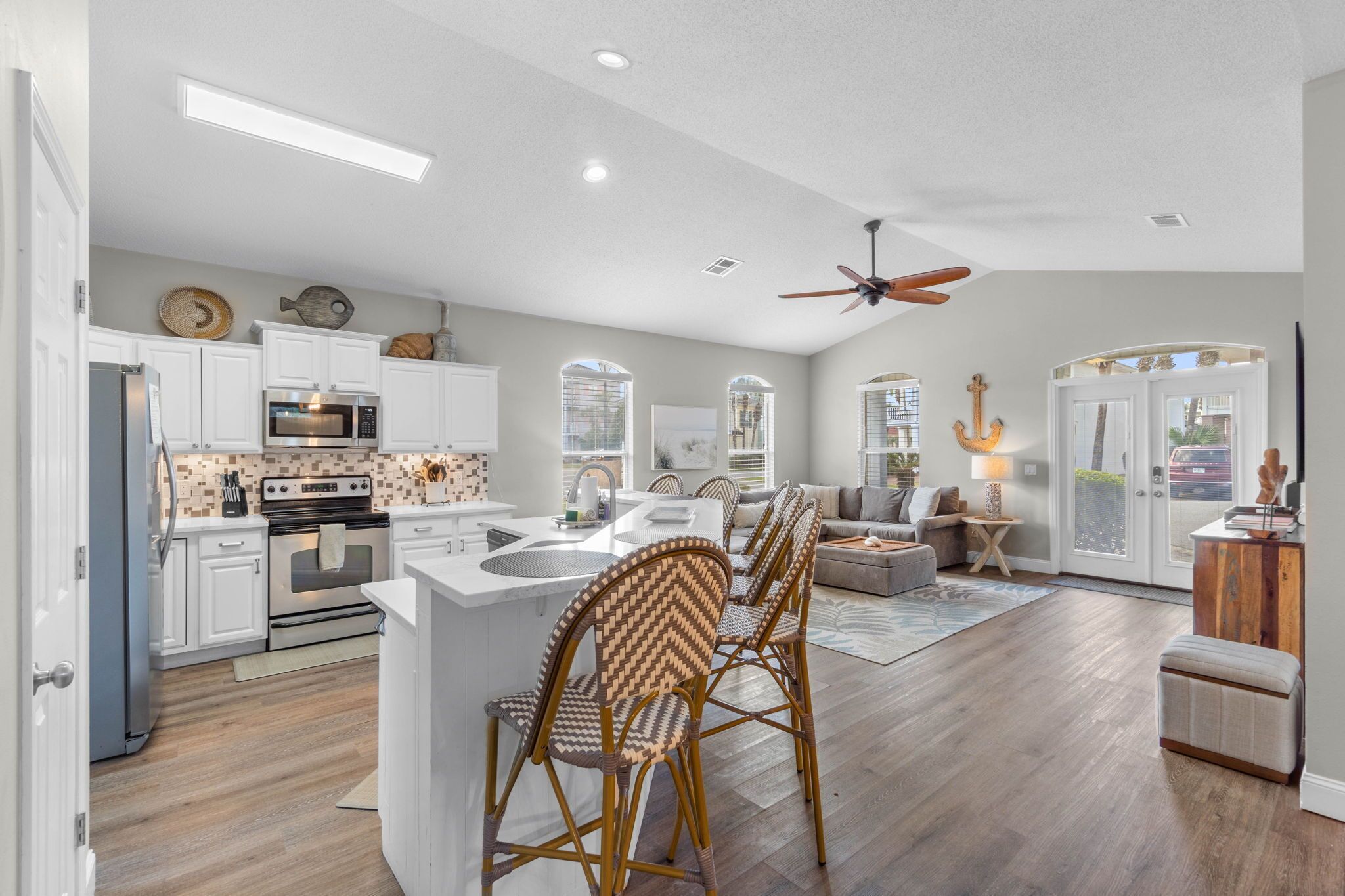 A modern kitchen with white cabinets, a built-in oven, and a microwave.
