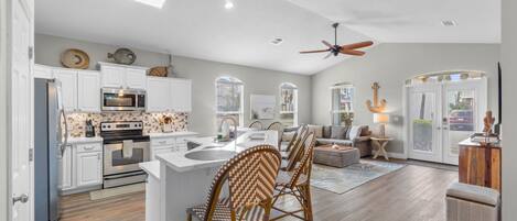 A modern kitchen with white cabinets, a built-in oven, and a microwave.