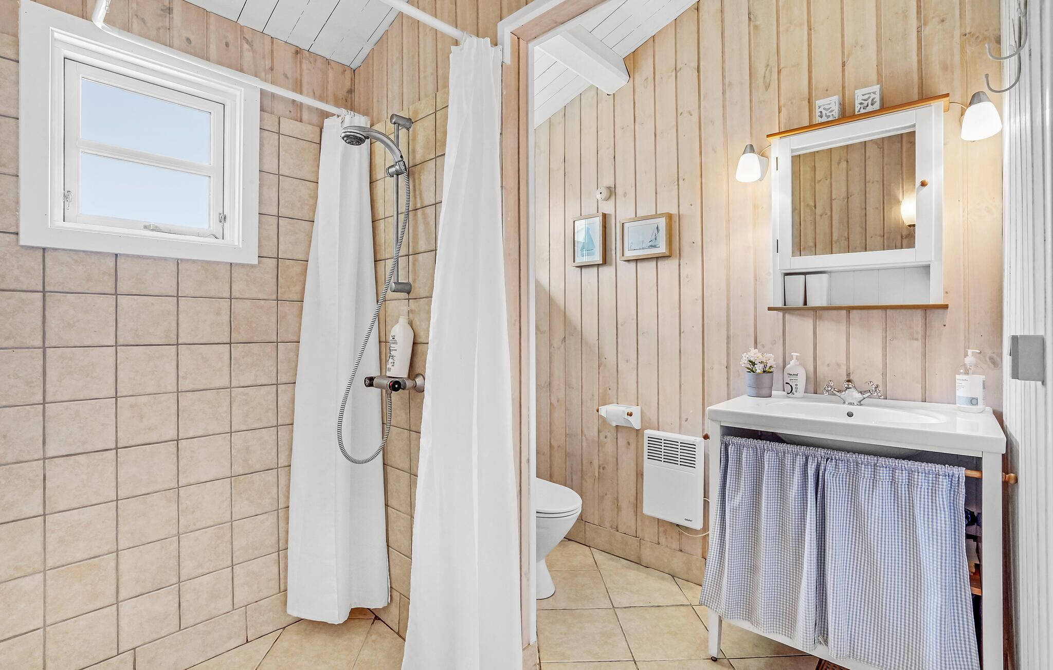 A bathroom with a shower, toilet, sink, and a mirror.