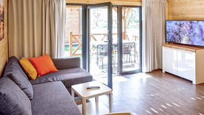 A modern living room with a grey sofa, a small table, and a TV. - Gorgeous home in Mrzezyno with swimming pool (Mrzezyno)
