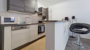 A modern kitchen with a microwave, stove, and sink. There is a bar stool and a coffee machine on the counter. - Gorgeous apartment in Pula with WiFi (Pula)