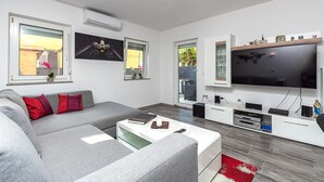 A modern living room with a grey sofa, a coffee table, a flat-screen TV, and a built-in entertainment unit with speakers. - Gorgeous apartment in Pula with WiFi (Pula)