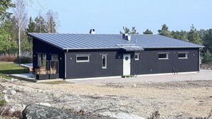 A modern, dark-colored building with a sloped roof, large windows, and a small porch area. - Nice home in Västervik with WiFi (Västervik)