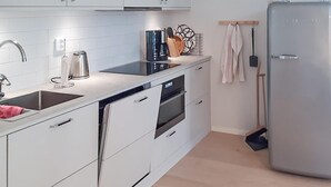A modern kitchen with white cabinets, a stainless steel sink, a coffee maker, and a broom leaning against the wall. - Nice home in Västervik with WiFi (Västervik)