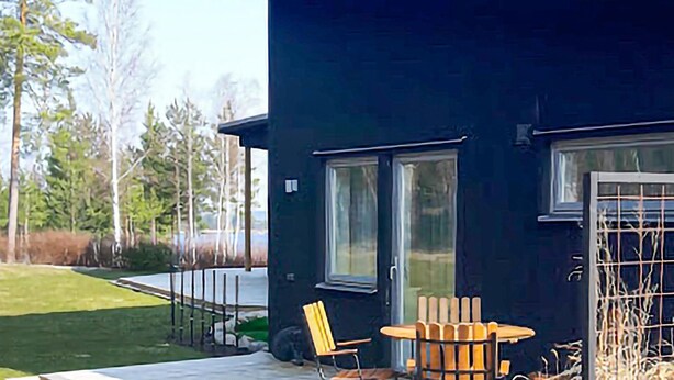 A modern black building with a patio area featuring a table and chairs. - Nice home in Västervik with WiFi (Västervik)