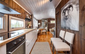A modern kitchen with wooden accents, a dining area with a bench, and a large wall painting. - 4 bedroom gorgeous home in Sjusjøen (Sjusjøen)