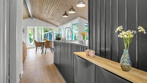 A modern kitchen with a wooden ceiling, pendant lights, a wooden countertop, and a view of the outdoors.