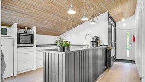 A modern kitchen with a wooden ceiling, white cabinetry, a central island, and pendant lighting.