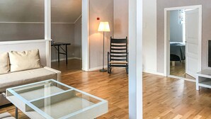 Una sala de estar moderna con un sofá, una mesa de centro de vidrio, una lámpara de pie y una silla.