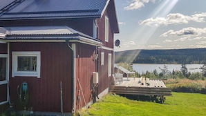Una casa de madera roja con vistas a un lago y un bosque.