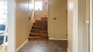 Una escalera de madera que conduce a una puerta con un pequeño ventanal en la parte superior.