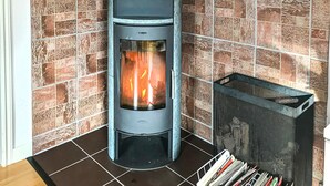 Una habitación de esquina con pared de baldosas de piedra y una chimenea moderna.