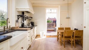 A kitchen with white cabinets, a wooden countertop, and a dining area with a table and chairs. - Stunning home in Bergen aan Zee (Bergen aan Zee)