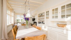 A spacious dining area with a long table, wooden chairs, and a vase of flowers. - Stunning home in Bergen aan Zee (Bergen aan Zee)