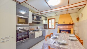Una cocina con electrodomésticos modernos, una mesa de comedor para cuatro personas y una chimenea.