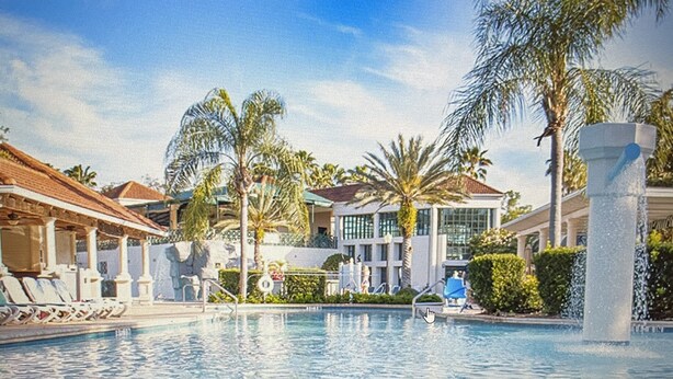 A swimming pool with a clear view of the surrounding buildings and palm trees.