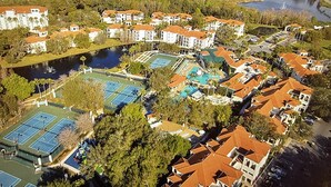 An aerial view of a residential area with multiple buildings, a large swimming pool, and a tennis court.