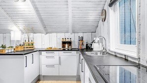 Une cuisine moderne avec des meubles blancs, un plan de travail noir et une fenêtre agrémentée de rideaux bleus.