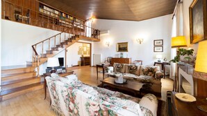 A spacious living room with a wooden staircase, a sofa set, a fireplace, and a bookshelf. - Lungarno attic with private terrace and lift (Firenze)