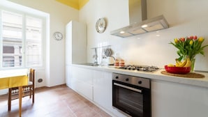 A kitchen with white cabinets, a stove, a sink, and a window with a view of buildings. - Lungarno attic with private terrace and lift (Firenze)