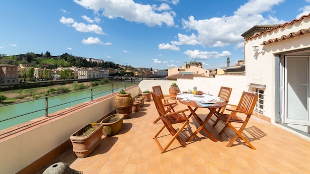 A terrace with a table and chairs, overlooking a river and cityscape. - Lungarno attic with private terrace and lift (Firenze)