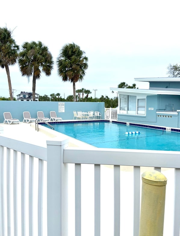 Relax by the pool surrounded by palm trees and lounge chairs.