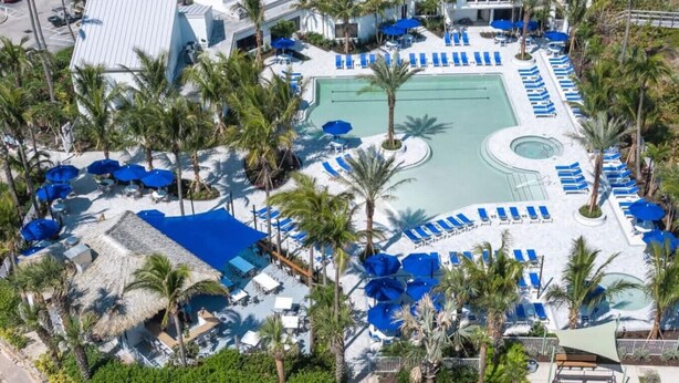Ein Resort mit einem zentral gelegenen Pool, Liegestühlen und Palmen.