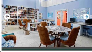 Eine Bibliothek mit Bücherregalen, einem runden Tisch mit Stühlen und einem Fernseher.
