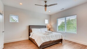 Ein Schlafzimmer mit Bett, Deckenventilator und großen Fenstern.