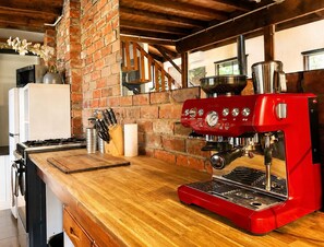 A kitchen with a red espresso machine, a brick wall, a wooden countertop, and a white refrigerator. - Top of the Otways - The Nature Lodge (Barramunga)