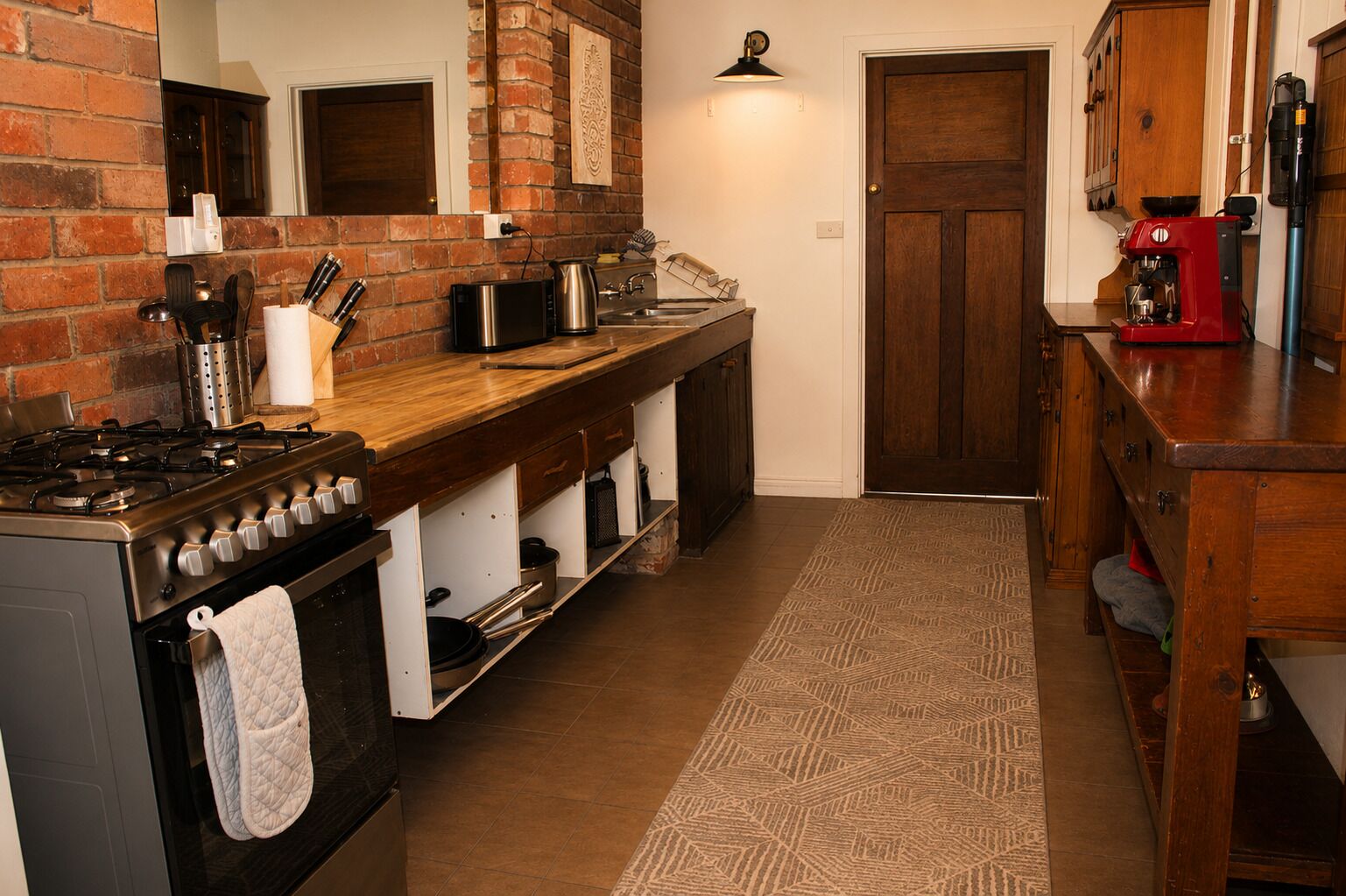 Une cuisine avec un mur en briques, une cuisinière, un évier et une machine à café.