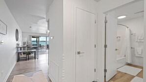 Moderni hotellihuone, jossa on suuri liukuovi, joka johtaa parvekkeelle, erillinen kylpyhuone ja ruokailutila, josta on näkymä merelle.