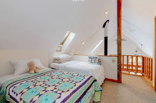 A bedroom with two beds, a large window, and a wooden balcony.
