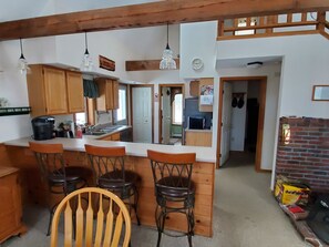 A compact kitchen with wooden cabinets, a coffee maker, and a bar area with stools.