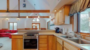 A spacious kitchen with wooden cabinets, a large island, stainless steel appliances, and pendant lighting. - Walk to pond / playground in pet friendly chalet while enjoying mountain views (Madison)