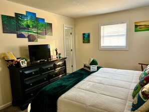 A bedroom with a bed, a dresser, a television, and wall art. - Perfect Poconos Retreat, .5 miles -Beach & Pool, Huge Game Room, Pet Friendly! (Hamlin)