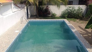 Une piscine rectangulaire avec un bord carrelé et un escalier en métal.