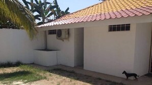 Un bâtiment d’un seul étage, avec un toit recouvert de tuiles rouges, une petite fenêtre et un mur en béton.