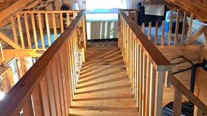A wooden staircase in a loft bedroom with a view of the sky. - Rustic, small and primitive cabin - Riverview Cabin, LLC (Muscoda)