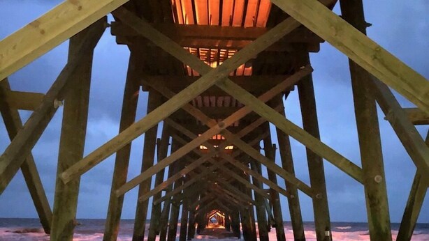 Eine Holzsteg-Konstruktion mit einem zentralen Weg, der zu einer Plattform mit einem Laternenaufbau führt.